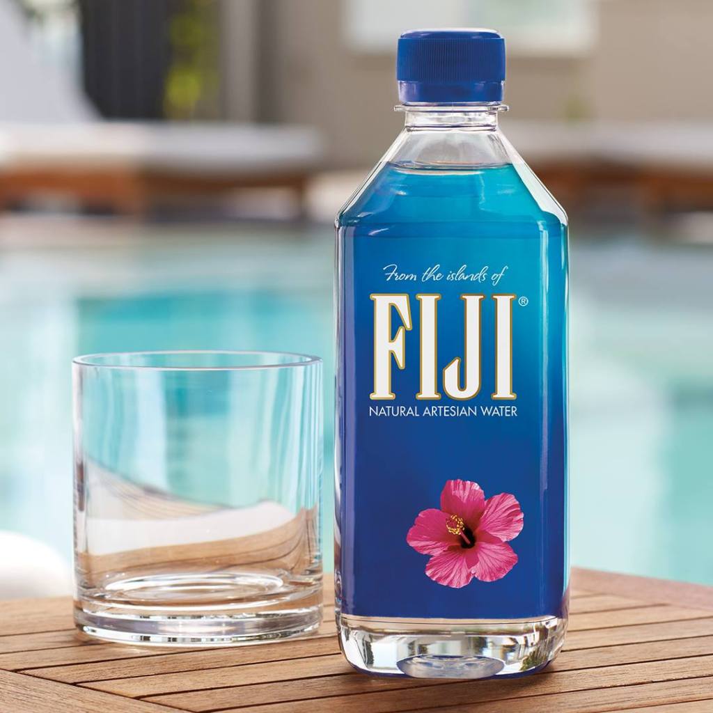 FIJI Water bottle next to a glass