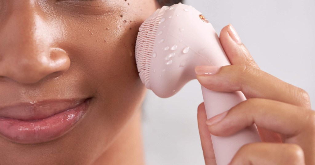 woman using pink facial scrubber on face