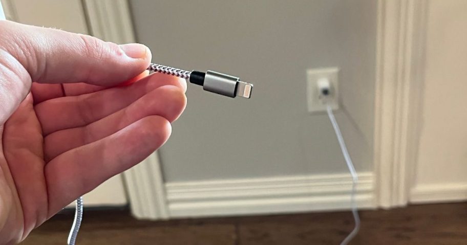 hand holding a charger plugged into wall