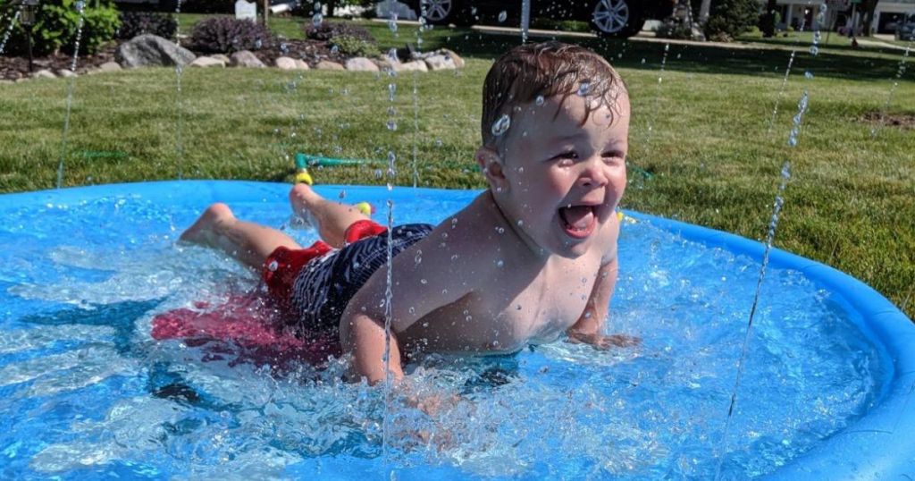Little boy having a blast laying on a splash bad