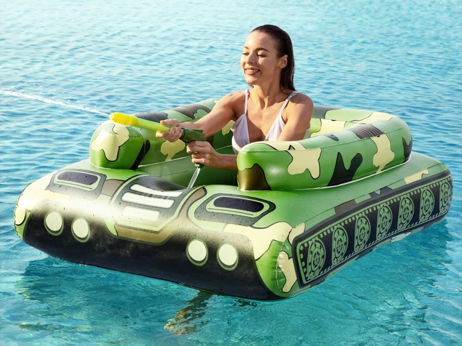 woman in an inflatable army tank pool float with water blaster