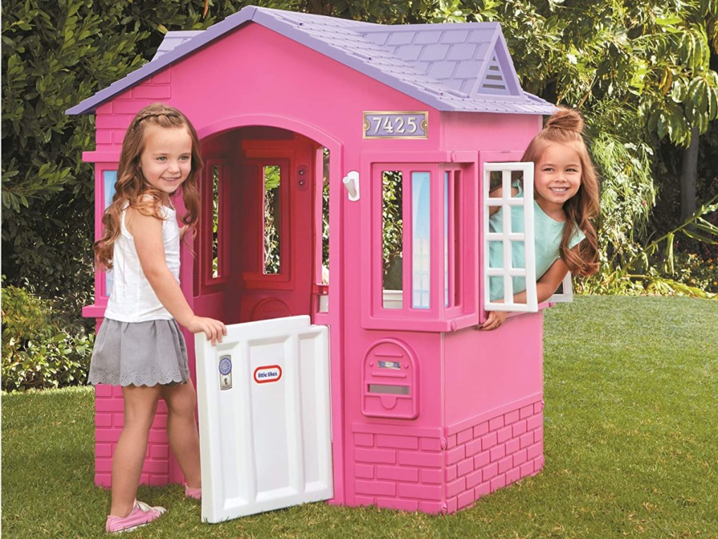 two girls in pink playhouse in yard
