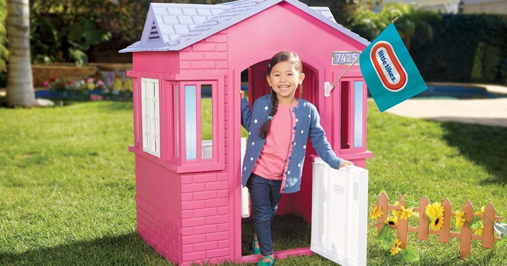 girl in pink playhouse in yard