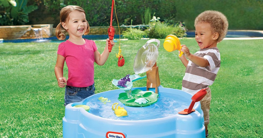 two kids playing outside with a water table