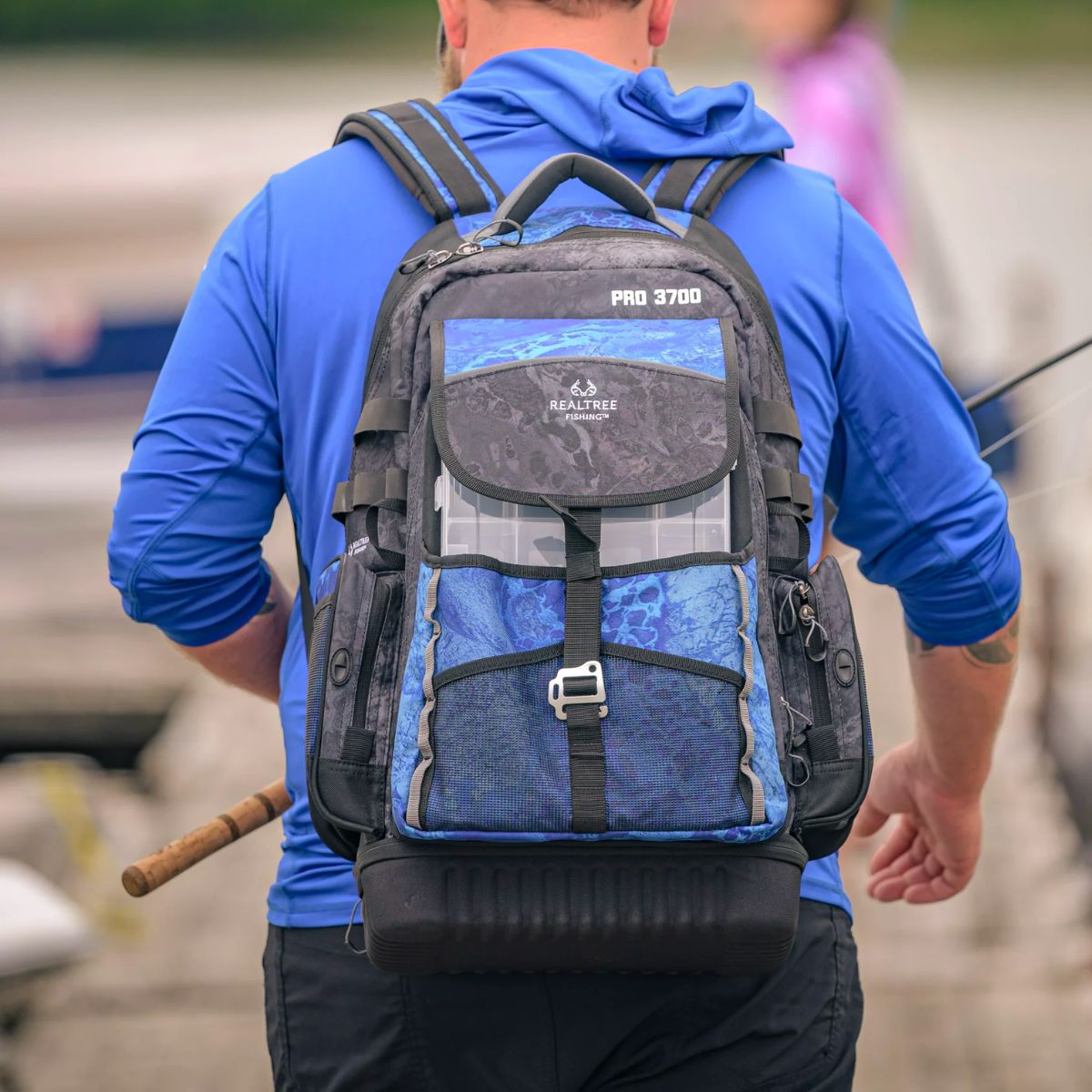 a man walking down a pier wearing a Realtree pro tackle Backpack