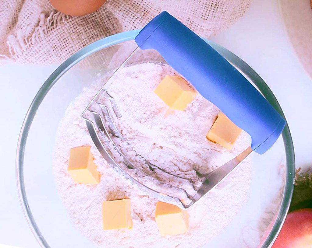 pastry cutter with blue handle in bowl of flour and butter