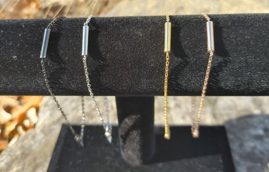 various silver and gold minimalist cremation bracelets on black velvet stand