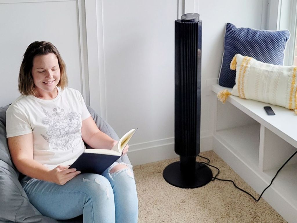 woman reading next to a tower fan