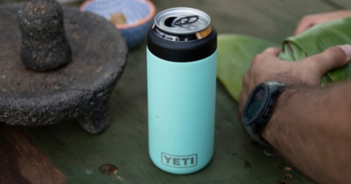 mint green yeti colster with a can inside next to a hand folding banana leaves
