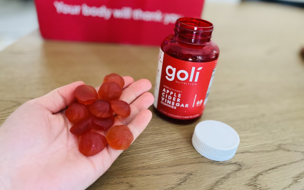 woman holding a handful of gummies in her palm with goli bottle in front of her 