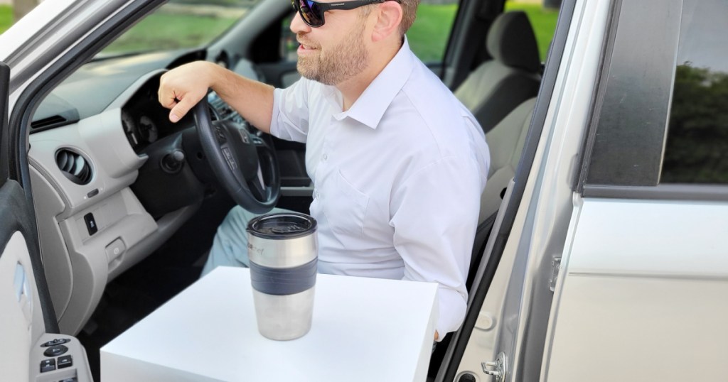 man getting out of a car with a travel mug on top of a white box