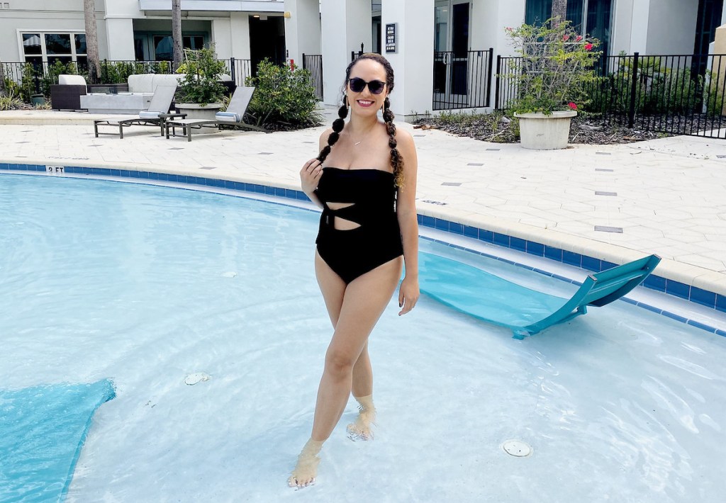 woman standing in swimming pool wearing black bathing suit