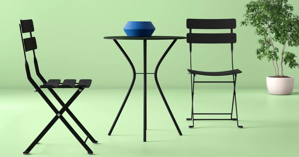 black bistro set with two chairs and table with blue bowl 