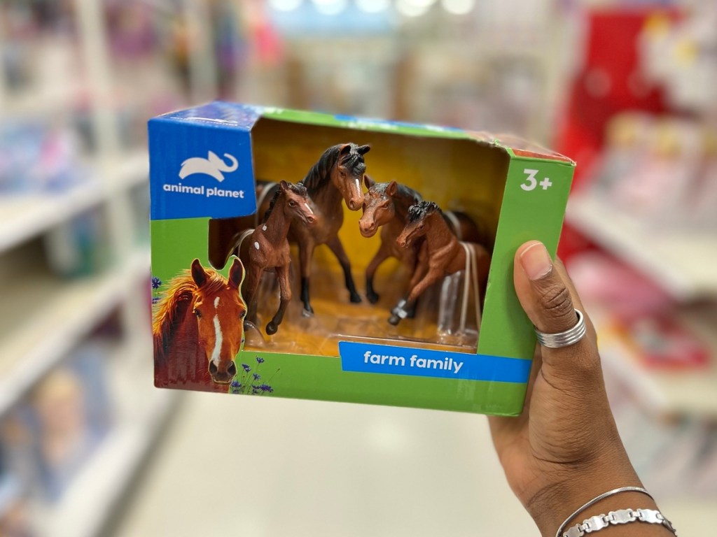 holding a set of toy horses in a green box