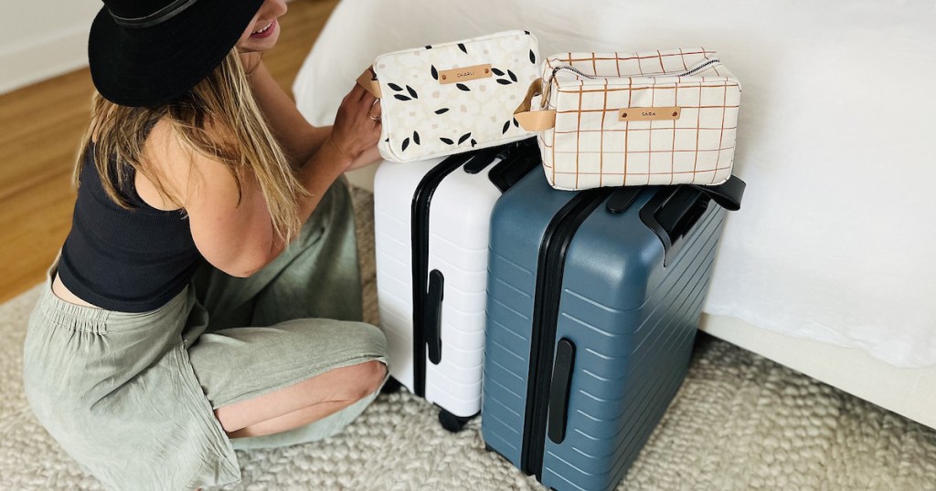woman kneeling next to white and blue away luggage suitcases 