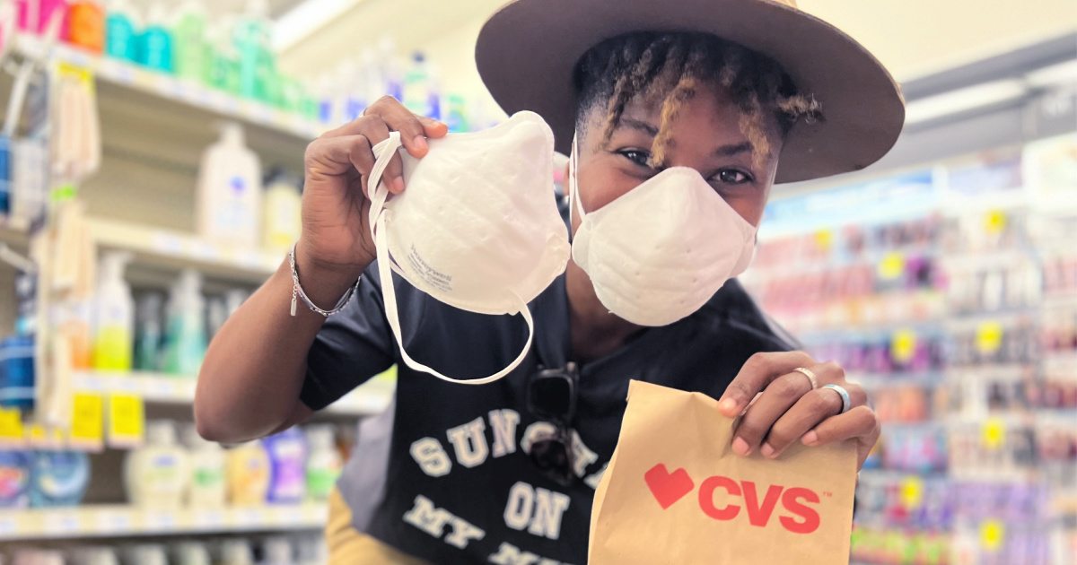 woman wearing and holding a face mask along with a cvs bag in a store