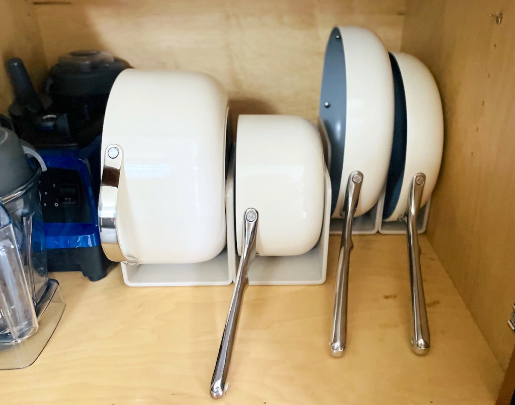 white pots and pans standing in cabinet organizers