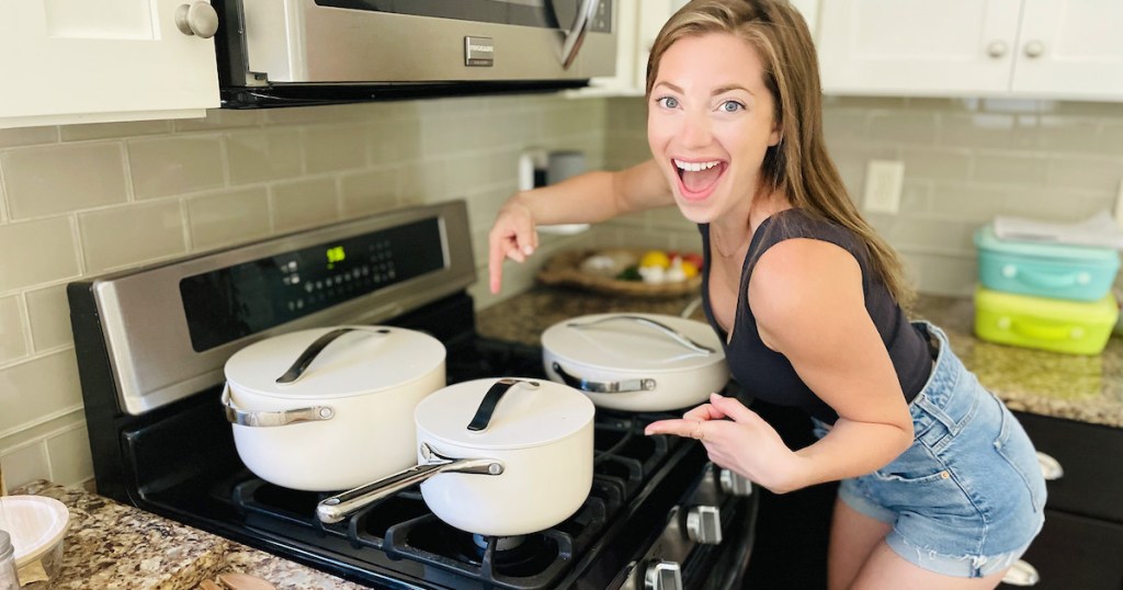 woman hovering over stove with white cookware set on top