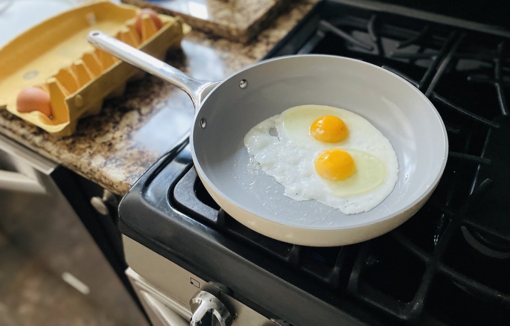 white caraway cookware pan with two sunny side eggs cooking inside