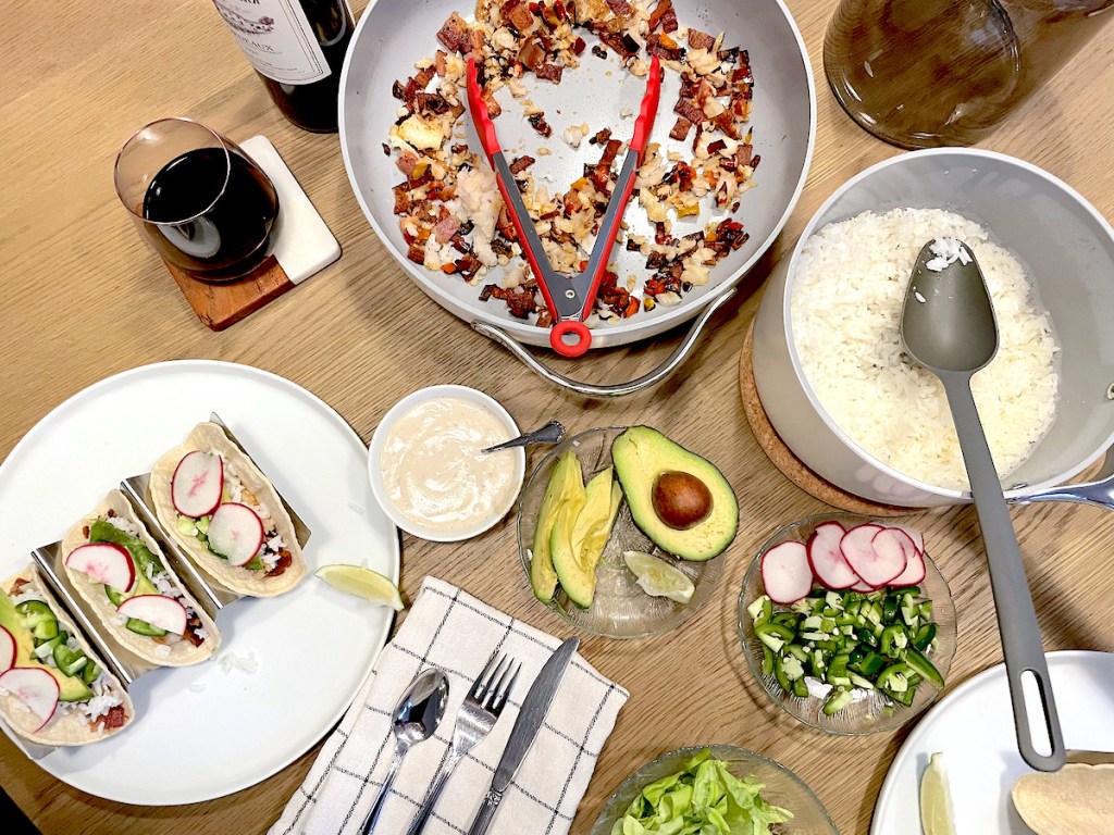 caraway pots and pans sitting on table with various taco toppings