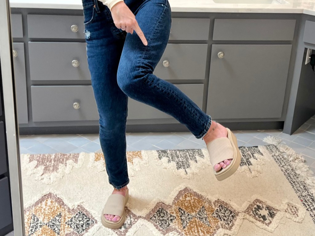 woman wearing jeans pointing at slide knit sandals