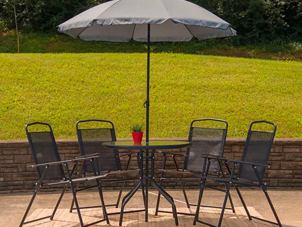 5 piece patio set with umbrella sitting next to pool