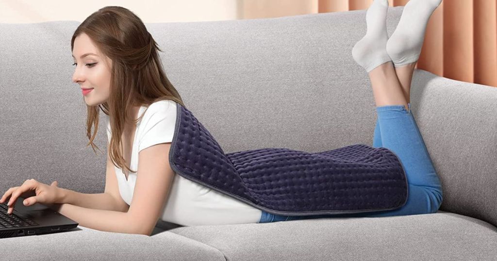 woman laying on couch with Evajoy Heating Pad on her back