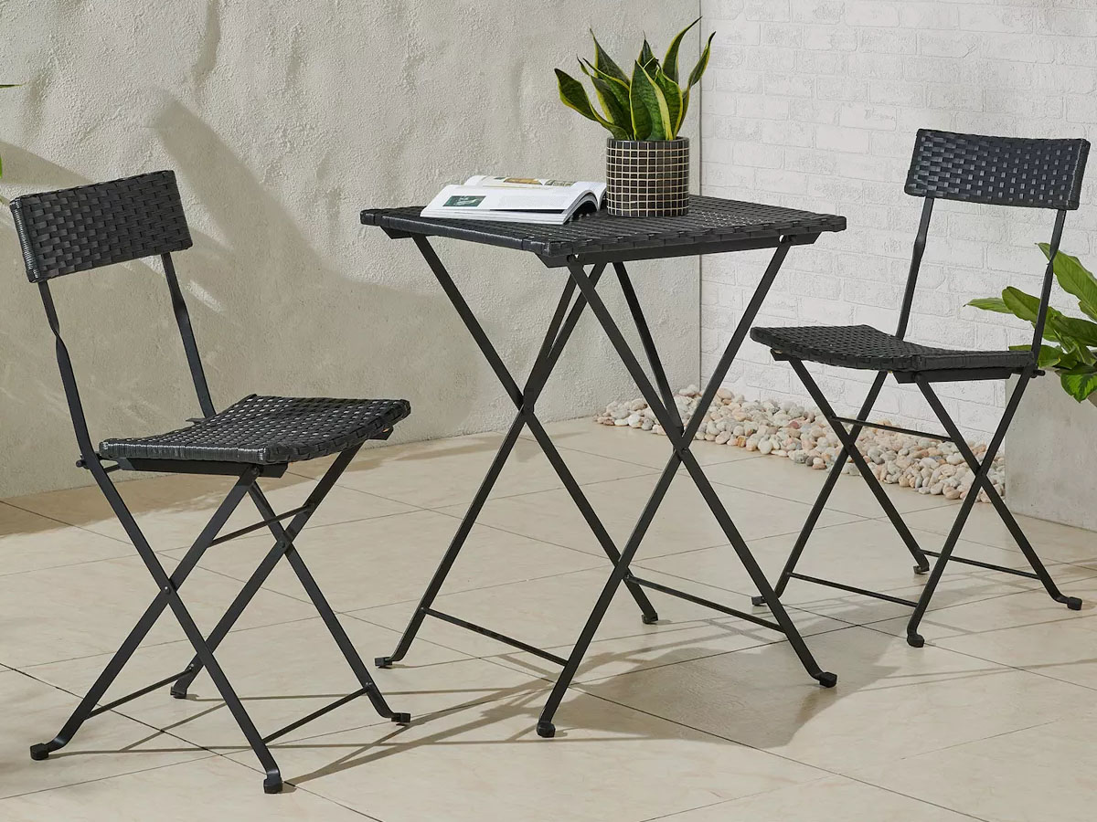 bistro set with two chairs and table with magazine and plant on it outdoors