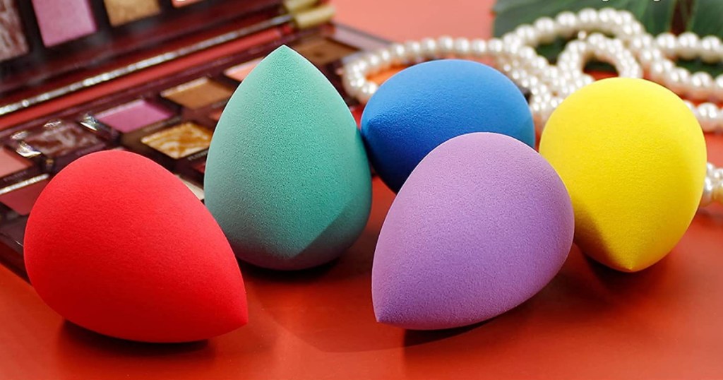 colorful makeup sponges on a table near makeup and jewelry