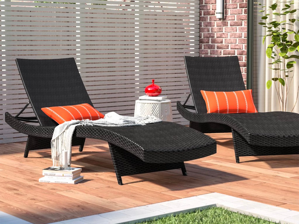 brown wicker lounge chaise chairs with orange pillows on pool deck