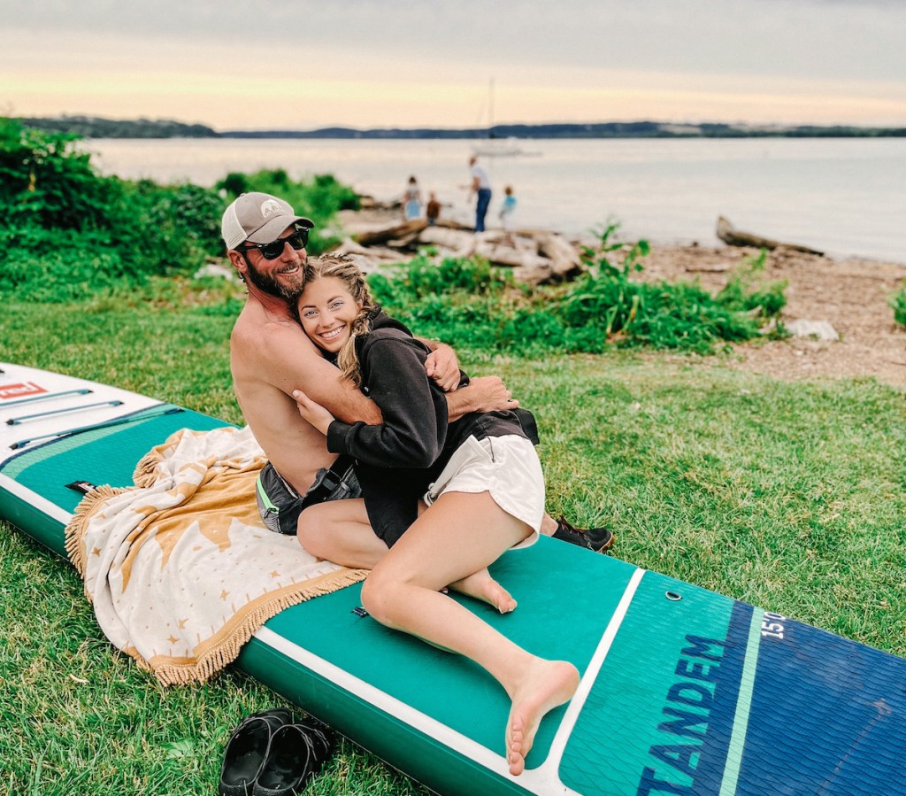 man and woman hugging while sitting on a paddleboard