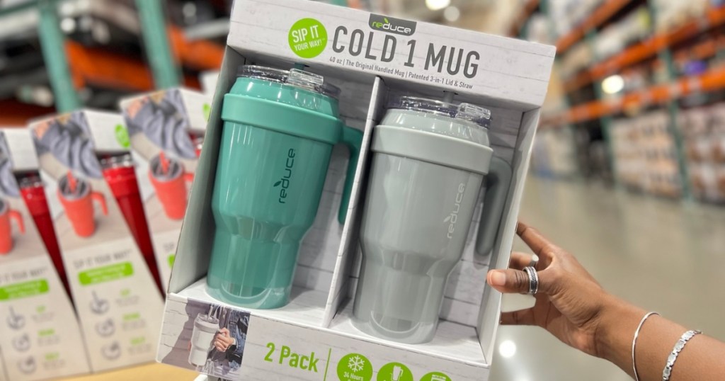 holding a 2-pack of metal cold mugs