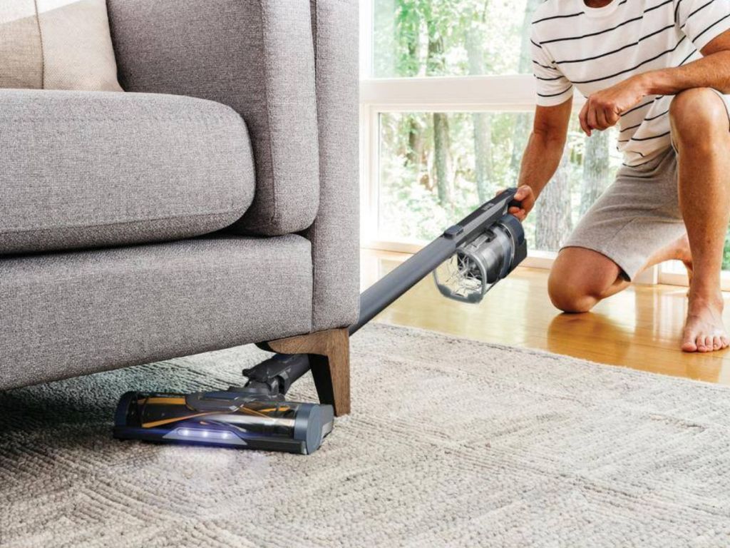 man vacuuming under couch