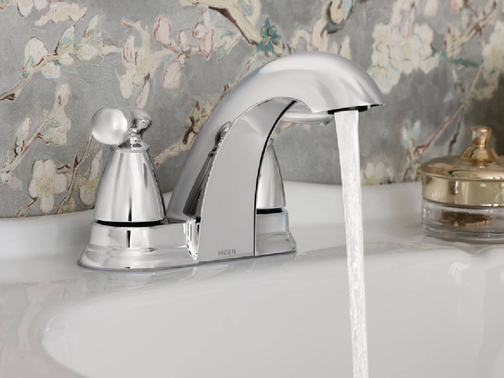 silver faucet opened with wallpaper in the background