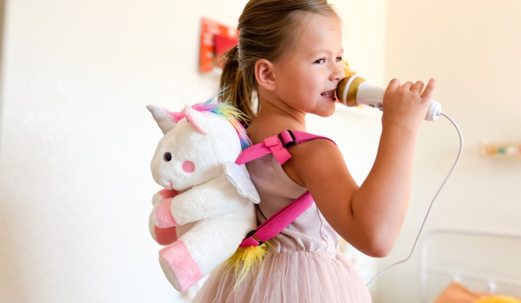little girls wearing a sing along crew plush unicorn
