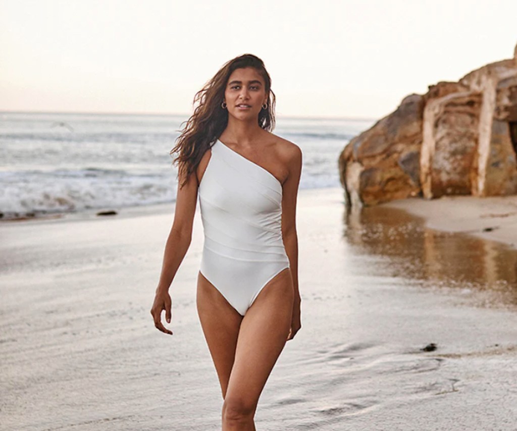 woman walking on beach wearing modest swimwear white one piece