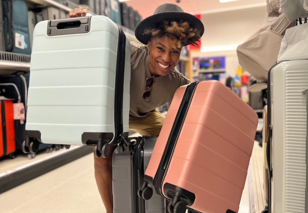 woman holding up white and pink suitcase