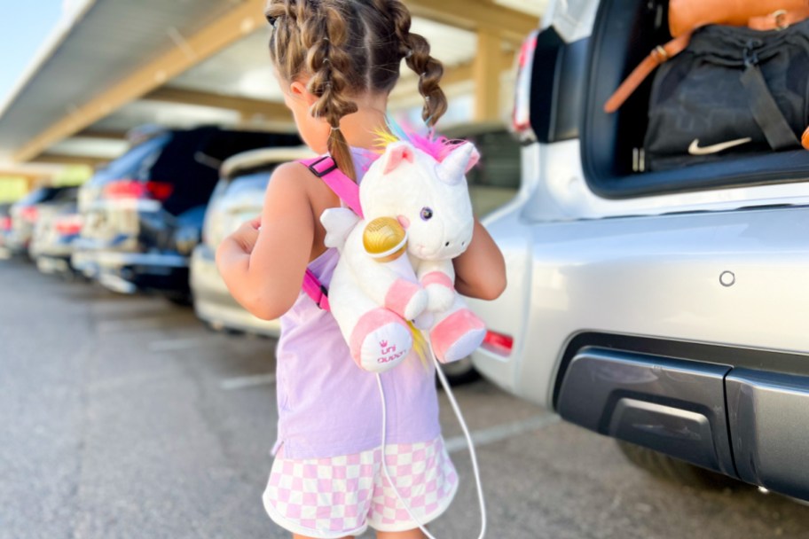 girl carrying unicorn backpack in parking lot