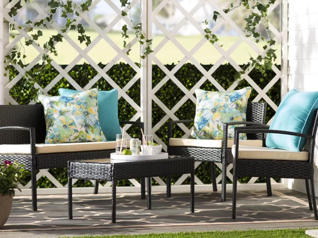 black wicker patio set with beige cushions and teal and green pillows