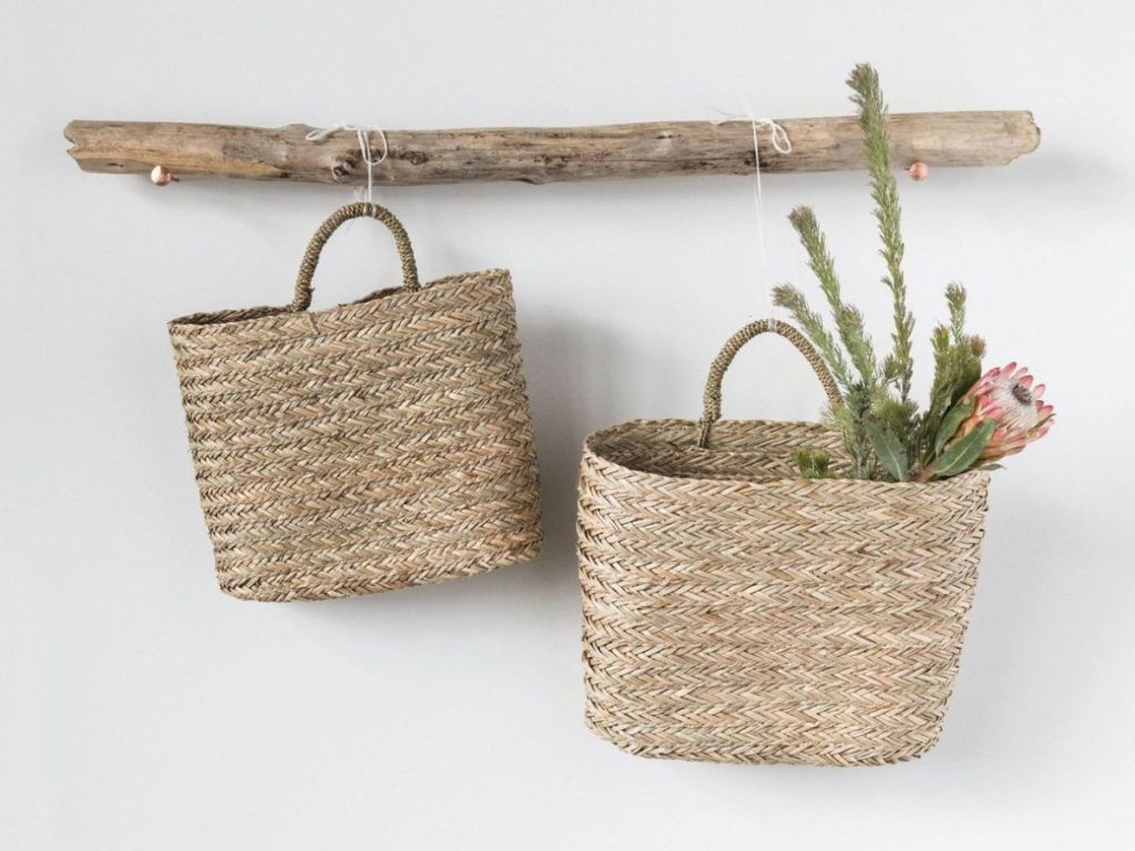 2 woven baskets hanging from wood decoration on wall
