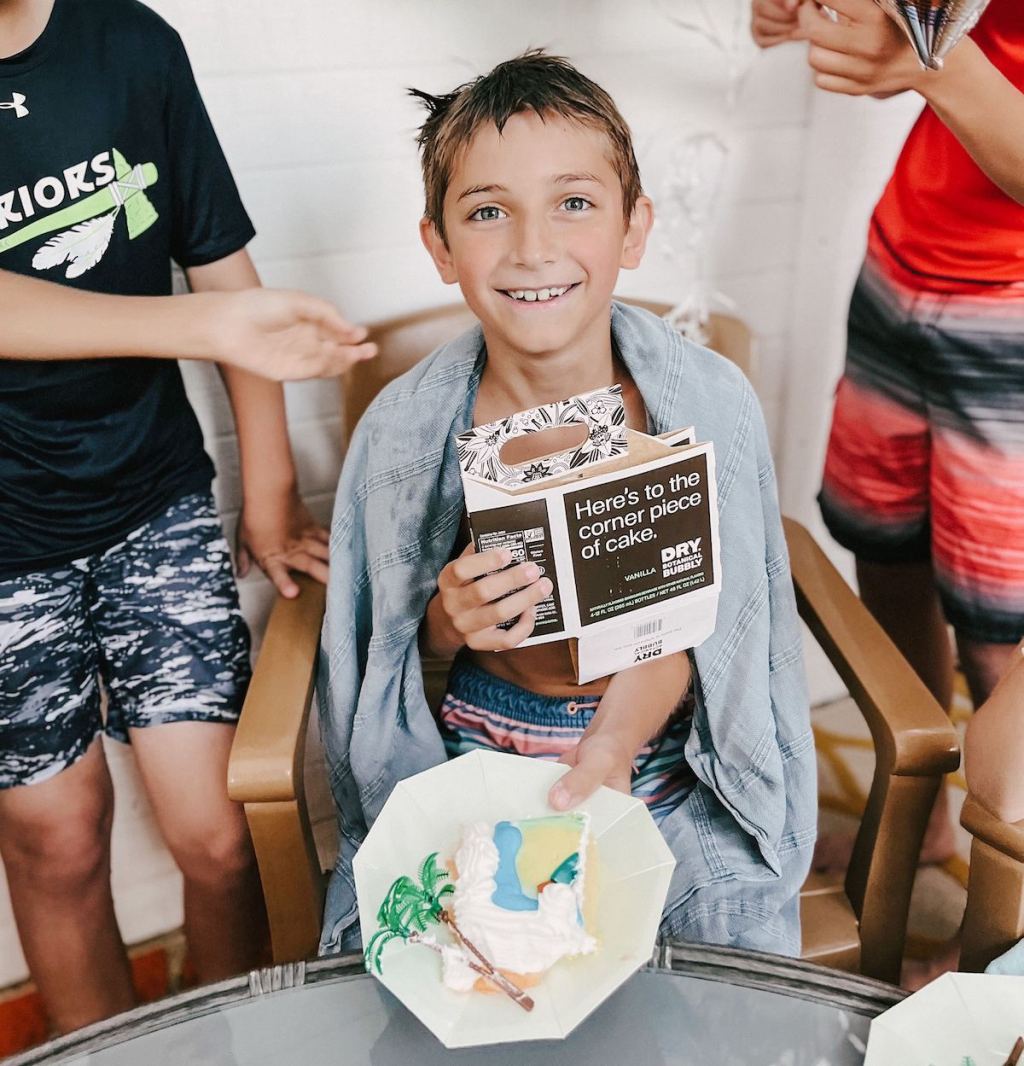 boy holding a piece of corner birthday cake in bathing suit