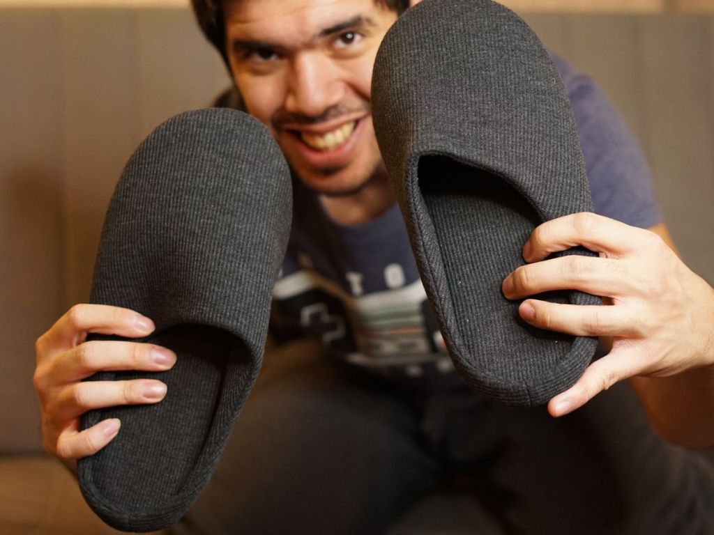 man holding up gray slippers