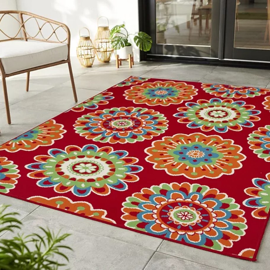outdoor patio space with large colorful floral medallion outdoor rug and tan wicker furniture