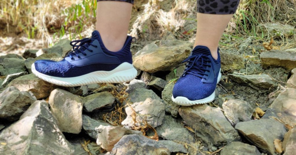 woman wearing blue walking shoes on rocks