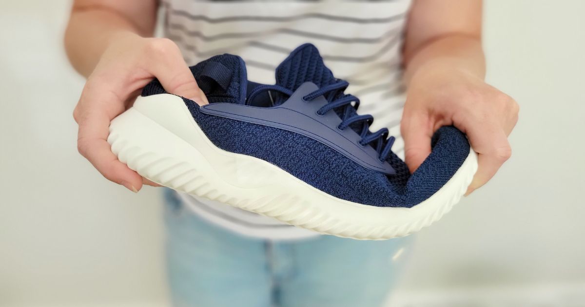 woman holding and bending blue walking shoes