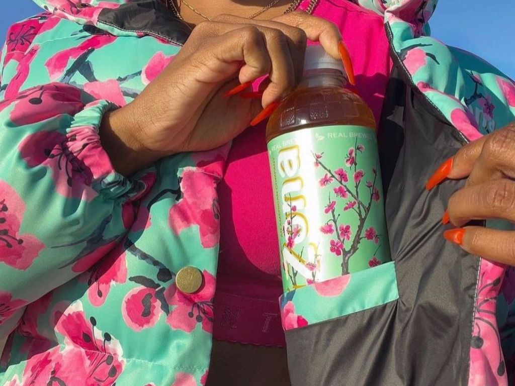 Woman putting an Arizona green tea bottle in her jacket pocket