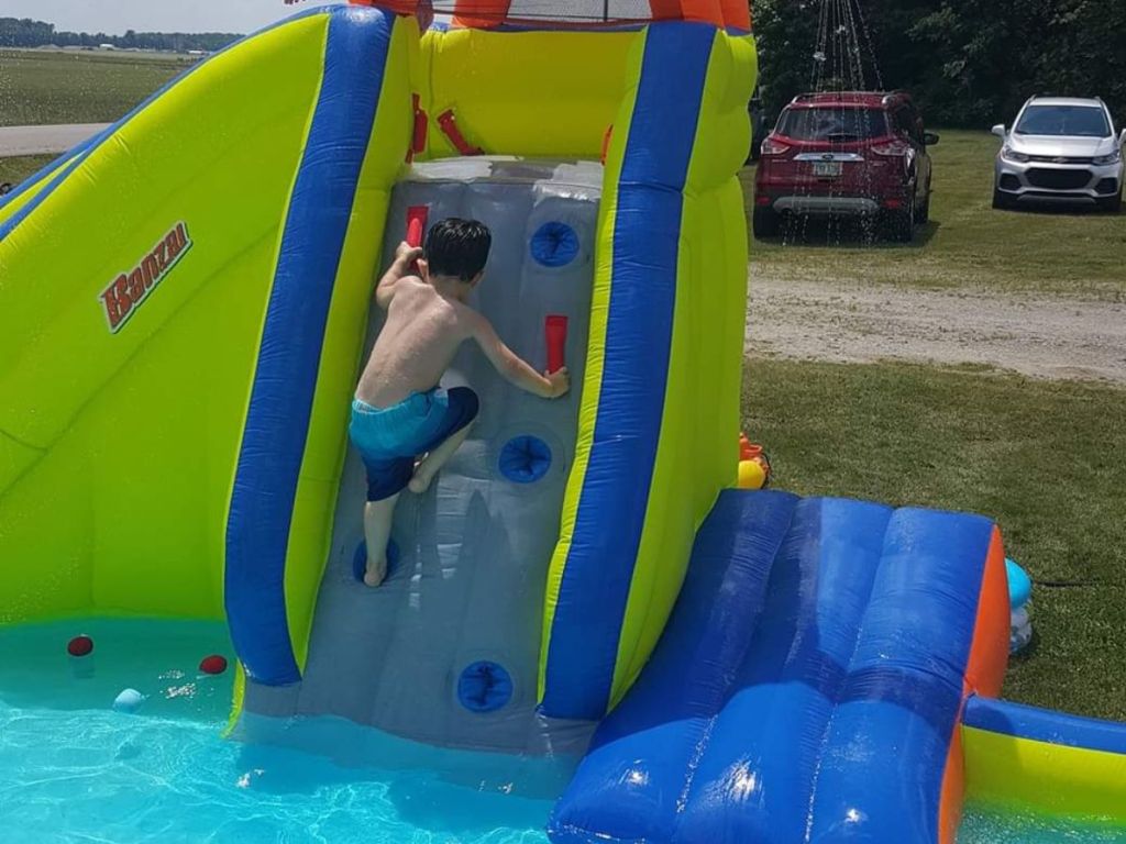 little boy climbing up to use the slide on a Banzai inflatable water park