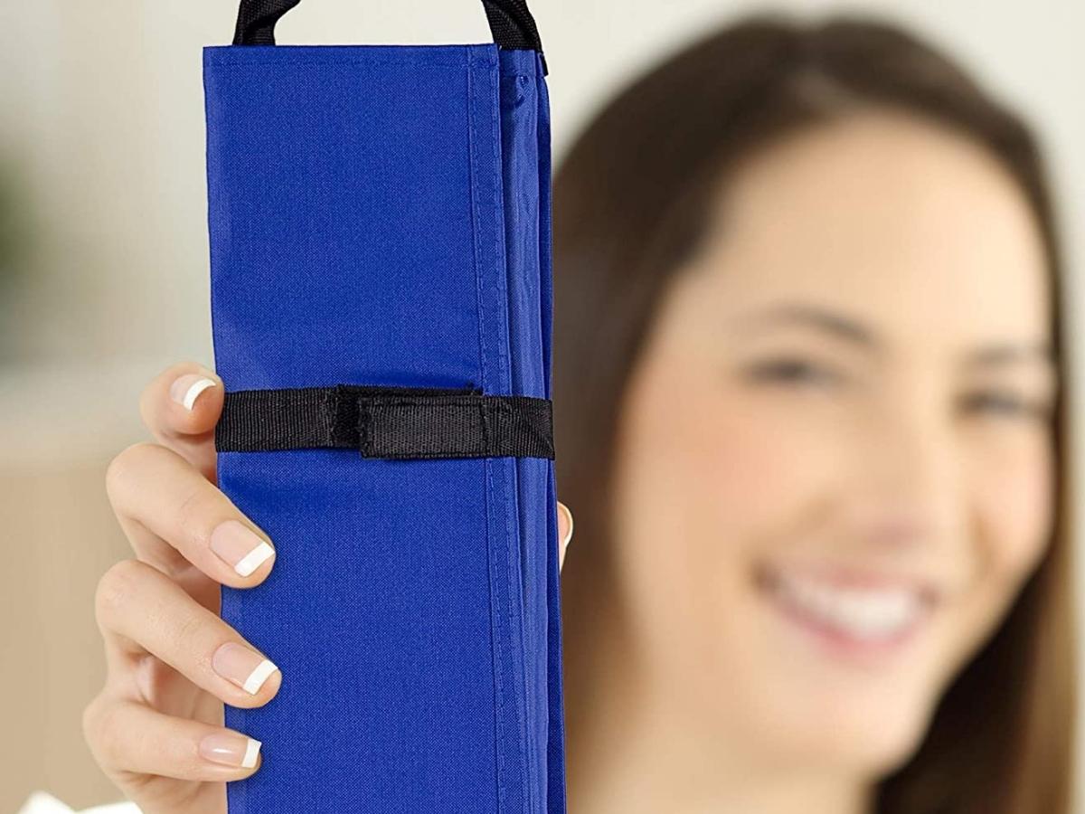 a woman holding up a folded and closed classroom border storage organizer