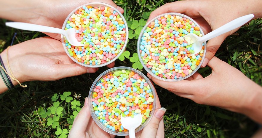 three sets of hands holding cups of dippin ddots