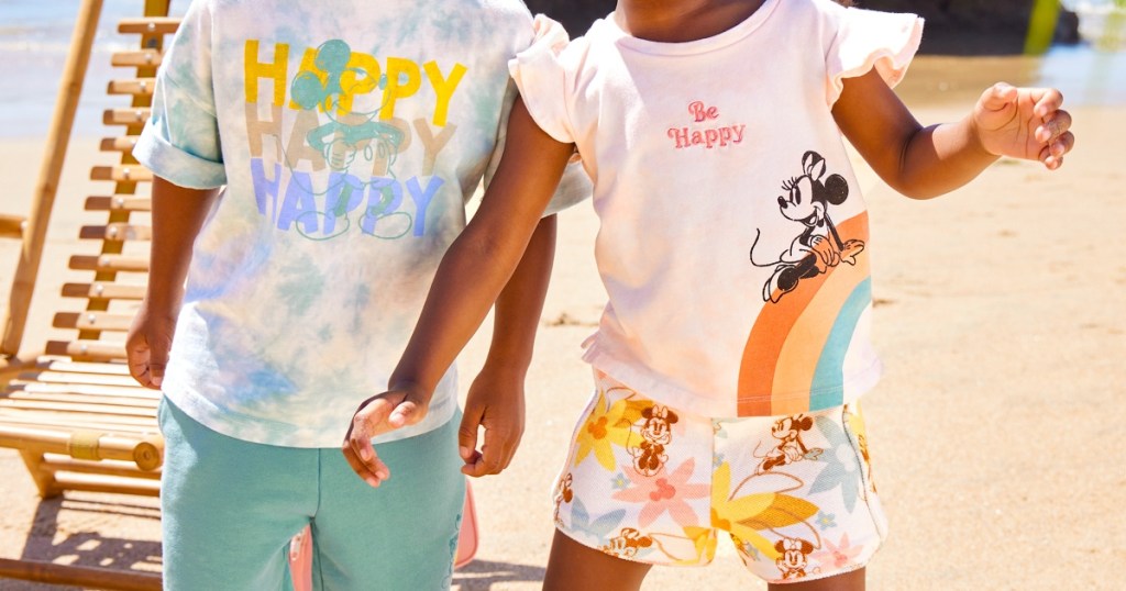 two children on beach wearing Disney clothing